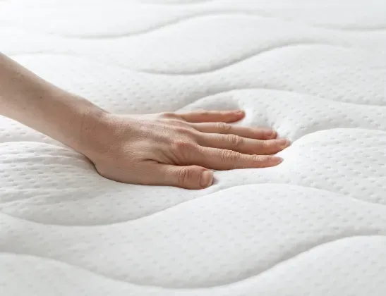 hands pushing down on mattress